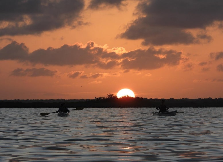 A sunset over a body of water with kayaks. 5