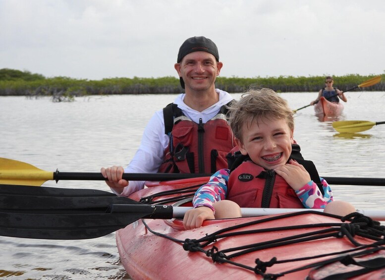Two people in a kayak on a calm body of water with vegetation in the background. 2