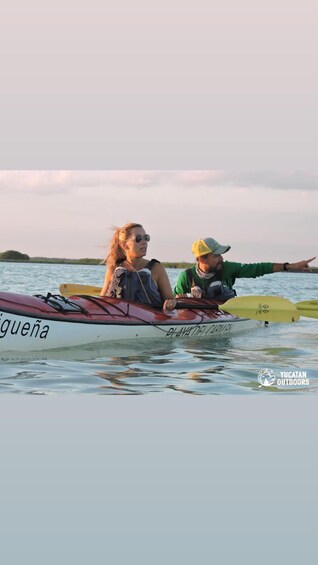 Two people kayaking on calm water with a distant shoreline. 4