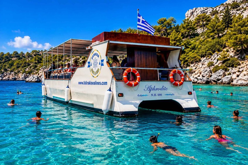 A boat named 'Aphrodite' with lifebuoys, passengers, and clear blue water. 1