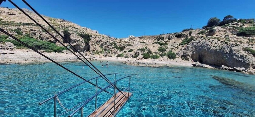 A clear blue sea with rocky terrain and a wooden dock. 2