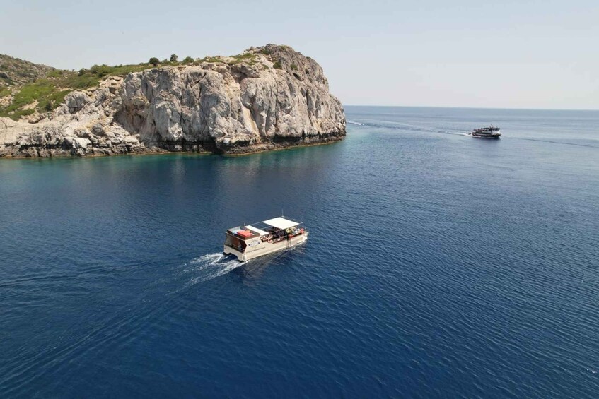 A boat on calm sea waters near a rocky coastline. 5