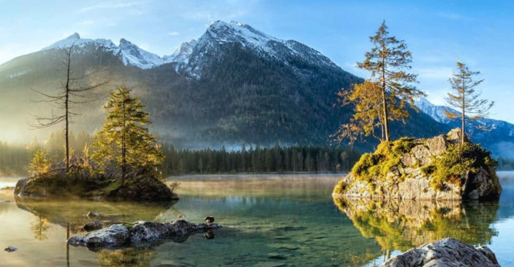 A calm lake with clear water, surrounded by mountains and trees. 2