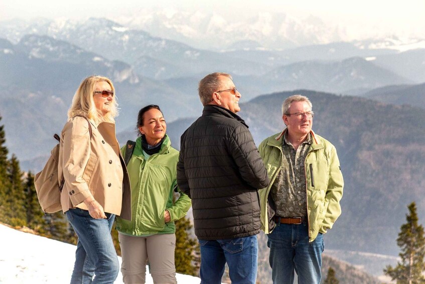A group of people standing on a snowy mountain with a mountainous landscape in the background. 1