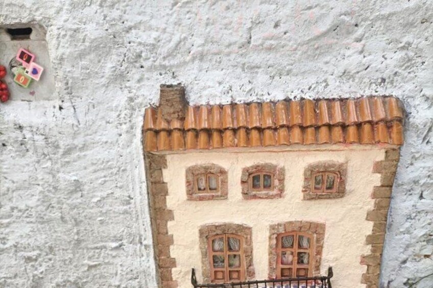 A textured wall with a small building model featuring a tiled roof and windows. 2
