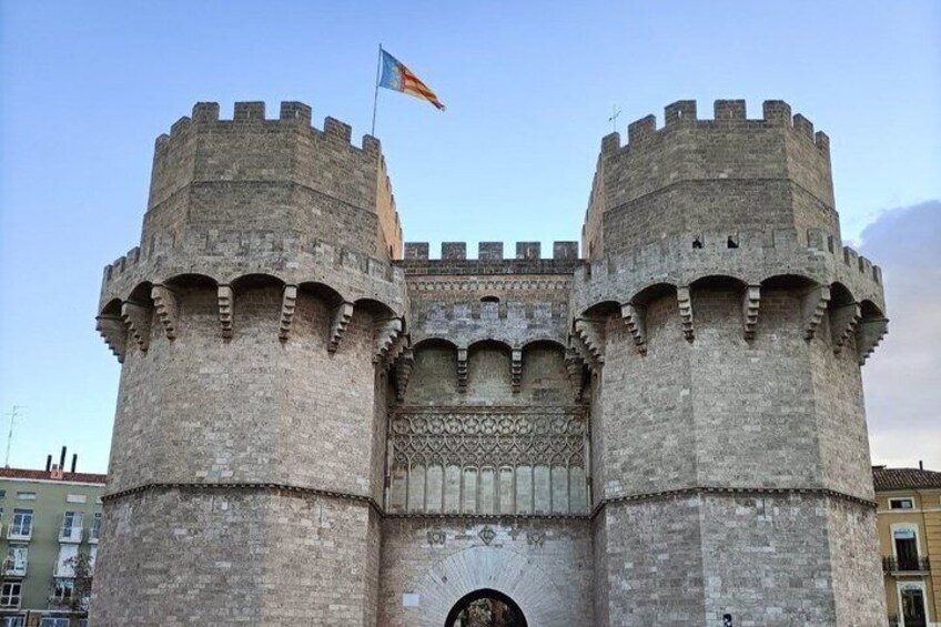 A historic stone castle with two round towers, a flag, and a decorative entrance. 3