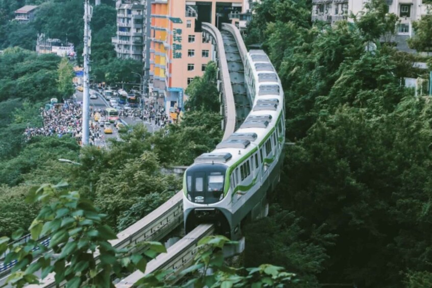 Un treno su un binario curvo, immerso nel verde e circondato da edifici urbani. 1