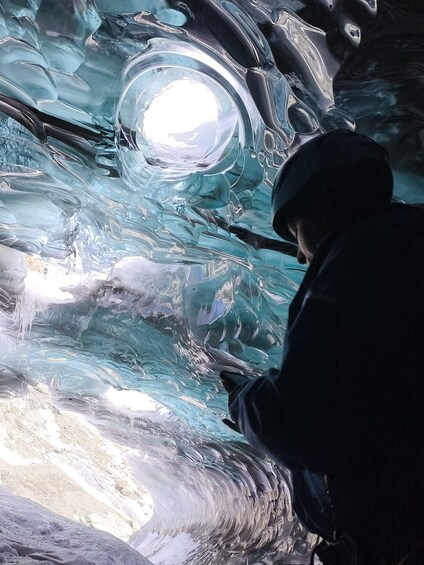 A person examining a large, transparent ice formation. 2