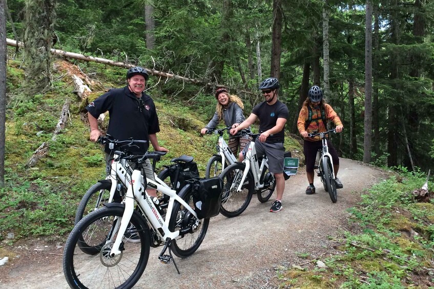 Four people on mountain bikes on a forest trail. 1