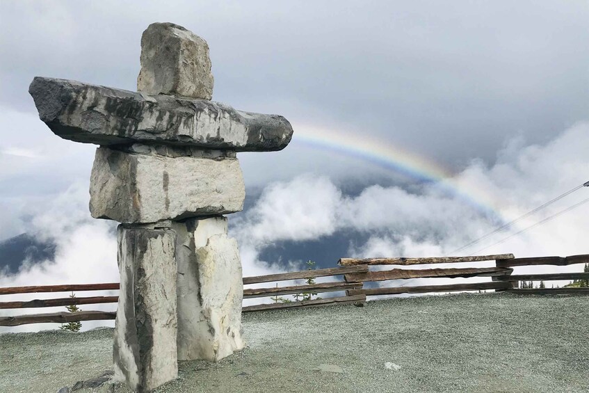 A stone cross with a rainbow in the background. 5