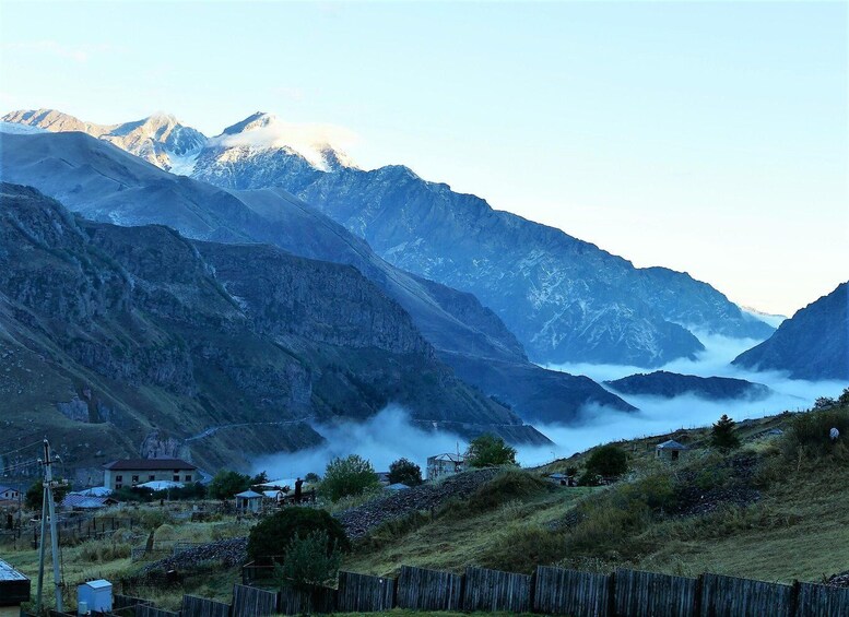 A mountainous landscape with a village nestled in the valley, surrounded by steep cliffs and a misty atmosphere. 3