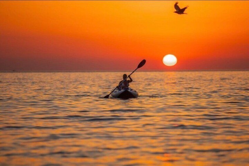 A kayaker on calm water during sunset. 1