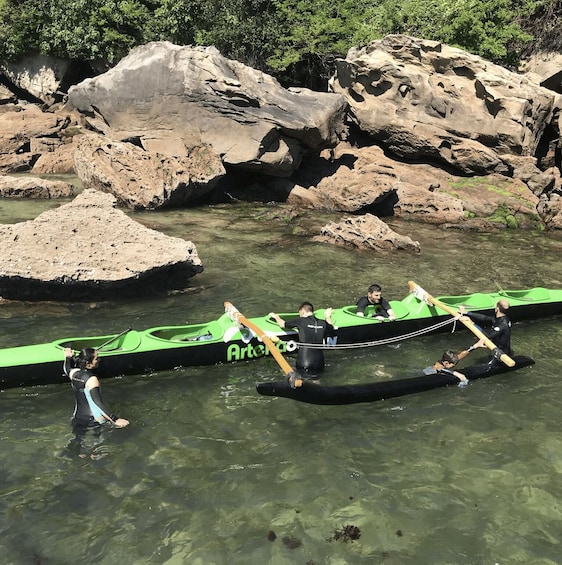 A group of people in a green boat on a river surrounded by rocks. 3