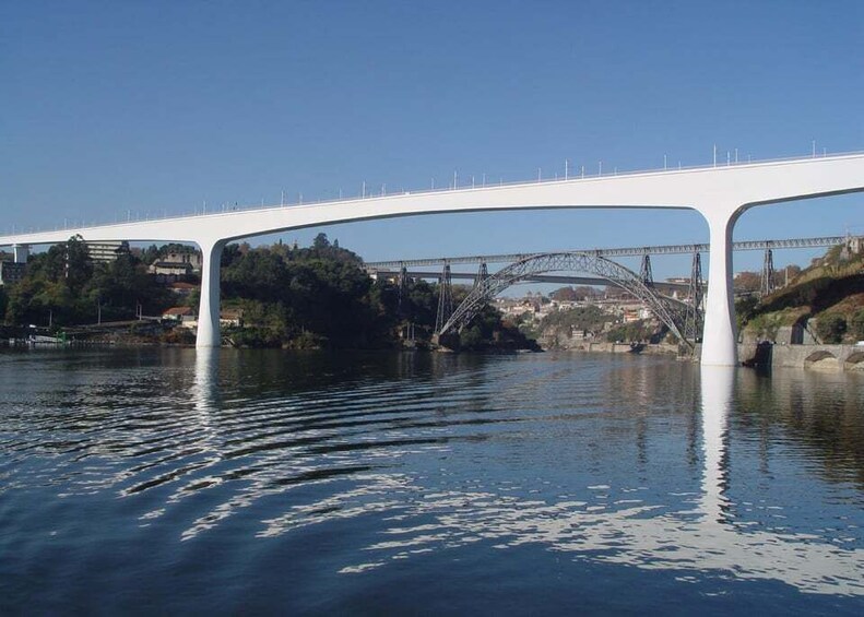 A white bridge over a river with a metal arch bridge in the background. 3