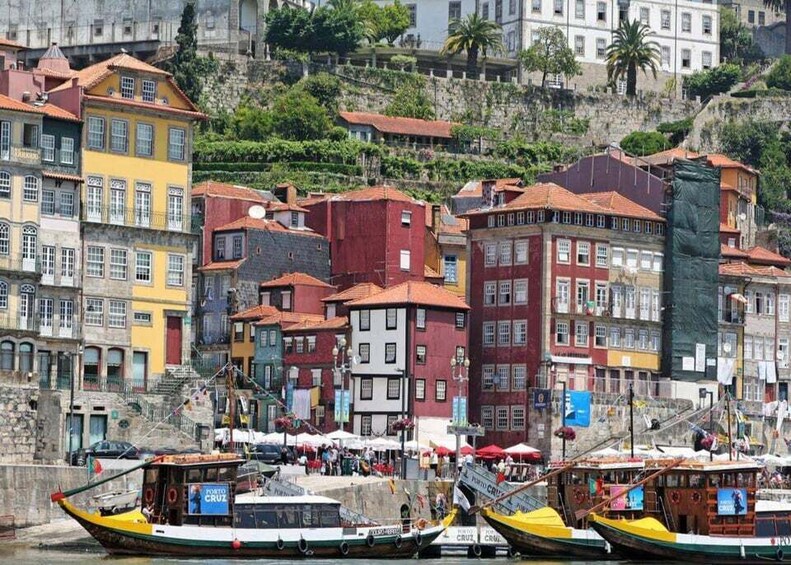 Colorful buildings along a waterfront, boats docked, and people near the water. 2