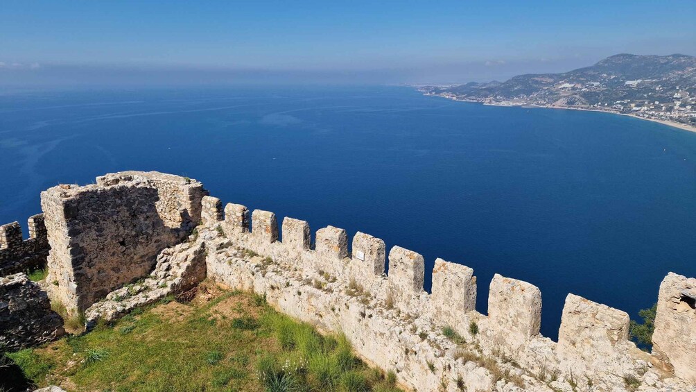 A coastal fortification with a clear view of the sea and a distant town. 2