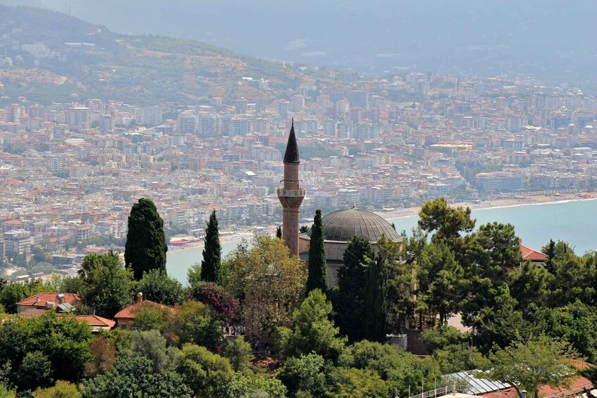 A mosque with a minaret and dome, surrounded by trees and overlooking a coastal cityscape. 3