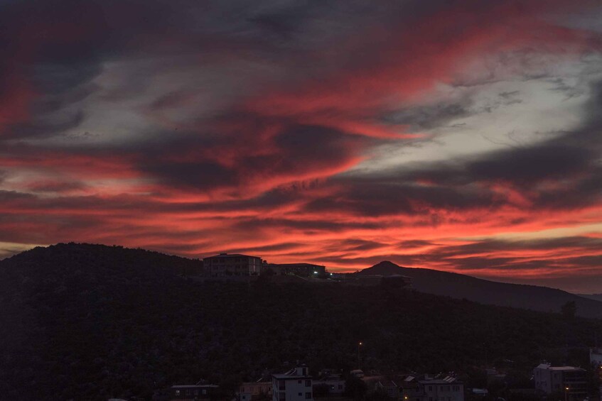 A sunset over a mountainous landscape with buildings on the hill. 4