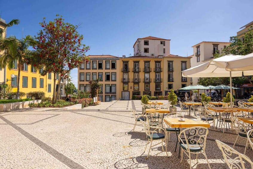 A cobblestone courtyard with outdoor seating, surrounded by multi-story buildings with balconies. 3