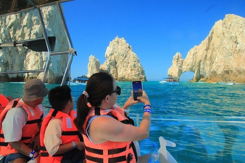 People on a boat wearing life jackets, with clear blue water and rock formations in the background. 5