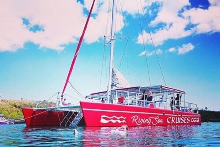 A red boat named 'Riding Son Cruises' on calm water. 2