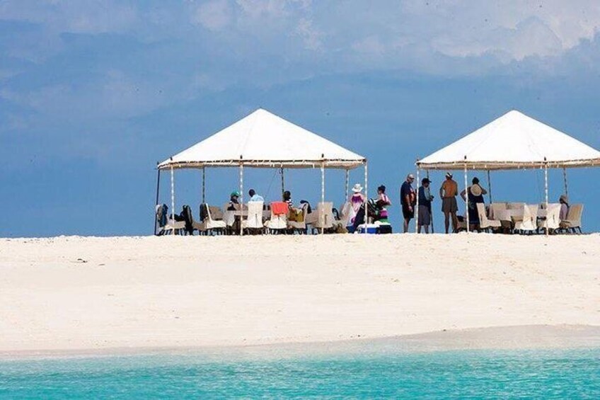 A beach with white tents and people under them. 1