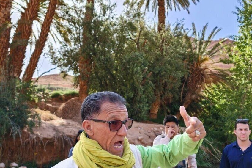 A person pointing with a hand gesture, surrounded by trees and a clear sky. 4
