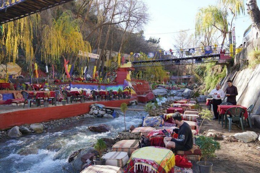 A riverside setting with tables and chairs, a bridge, and a colorful environment. 3