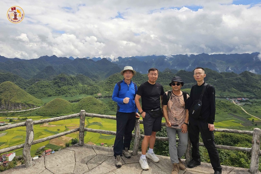 Four people standing on a stone platform with a view of terraced fields and mountains in the background. 5