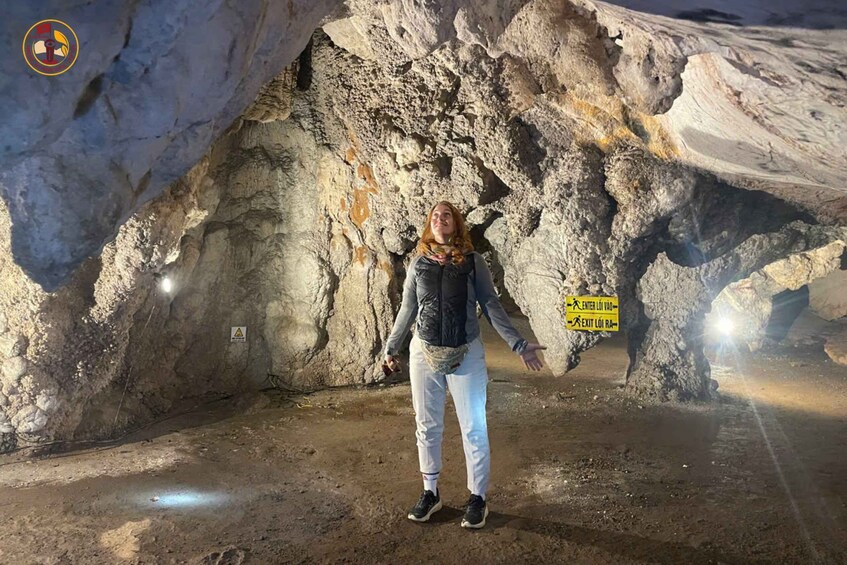 A person standing in a cave with a sign indicating an entrance and exit. 5