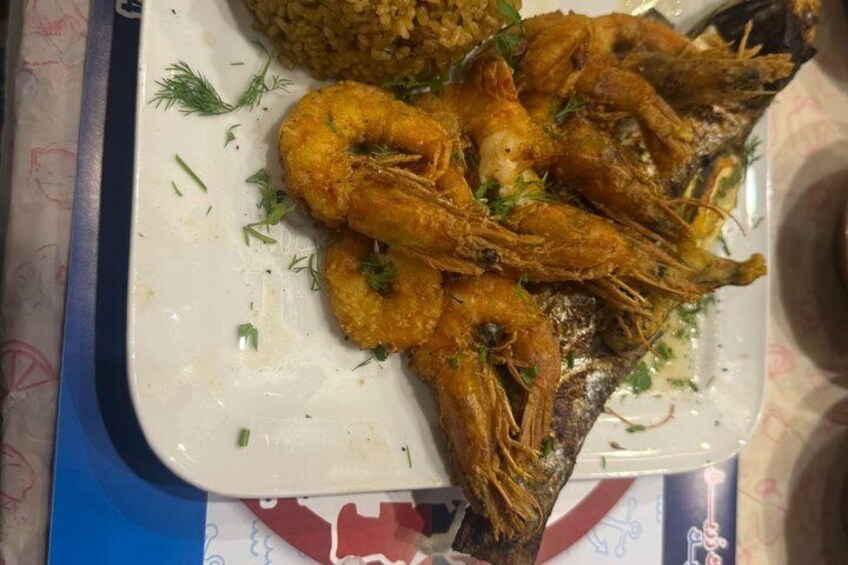 A plate with fried shrimp and rice garnished with herbs. 2