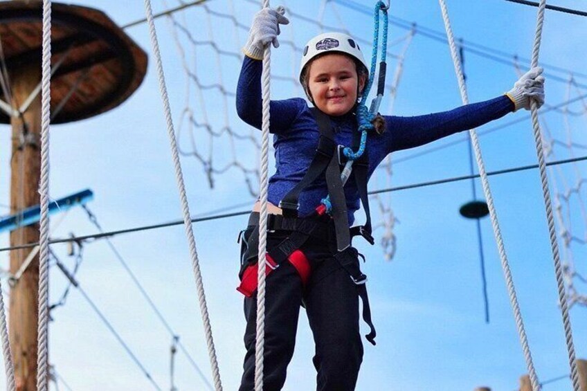 A person on a rope course with safety harness and helmet. 4