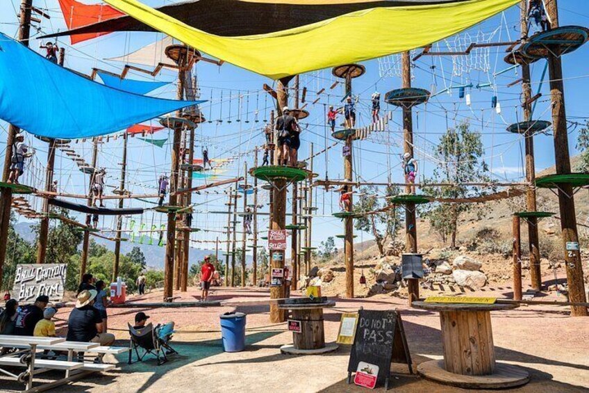 An outdoor adventure park with rope bridges, wooden structures, and a clear sky. 5