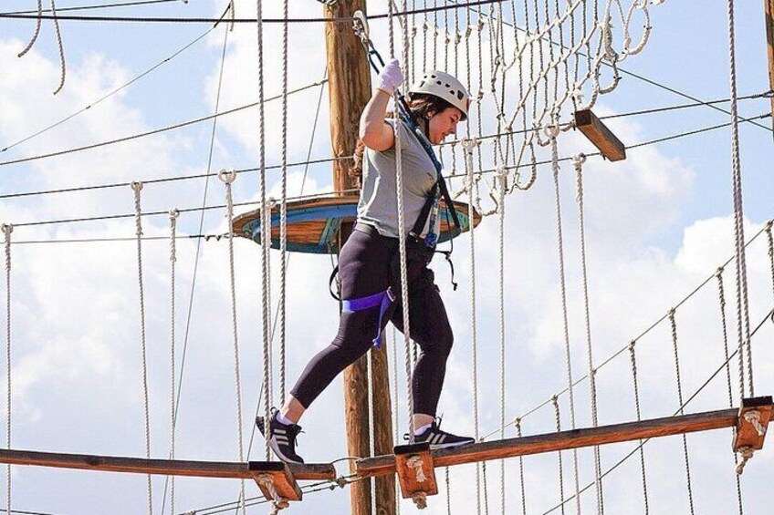 A person navigating an obstacle course with ropes and wooden planks. 3