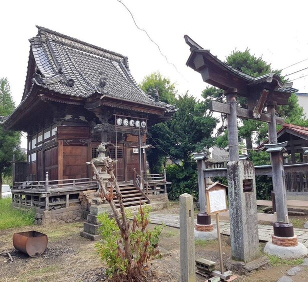 A traditional Japanese building with a tiled roof and wooden structure, surrounded by stone lanterns and a small tree. 5