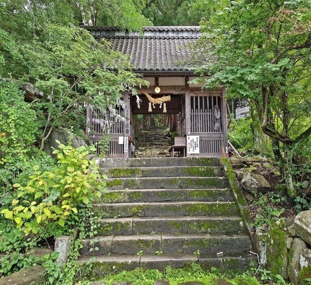 A traditional Japanese temple with a stone staircase leading up to a wooden gate. 4
