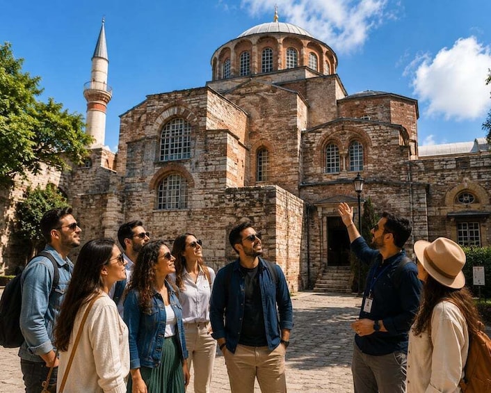 A group of tourists in front of a historic building with a prominent dome and minaret. 1