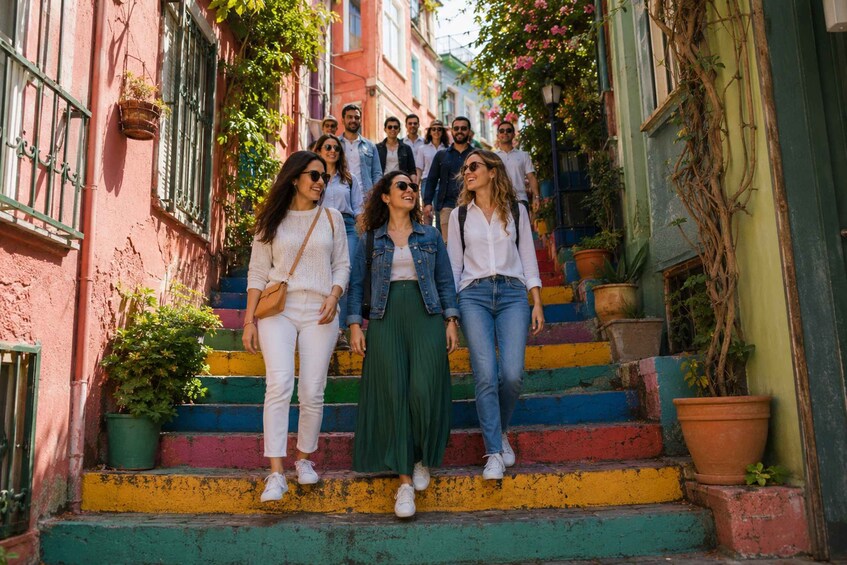A group of people walking up a colorful staircase in a narrow street with buildings on either side. 5