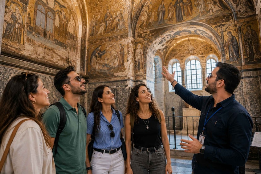 A group of people inside a historical building with detailed frescoes on the walls and arched windows. 2