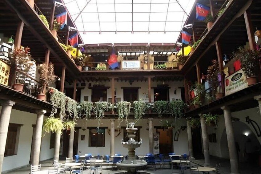A courtyard with a fountain, potted plants, and a tiled floor. 4