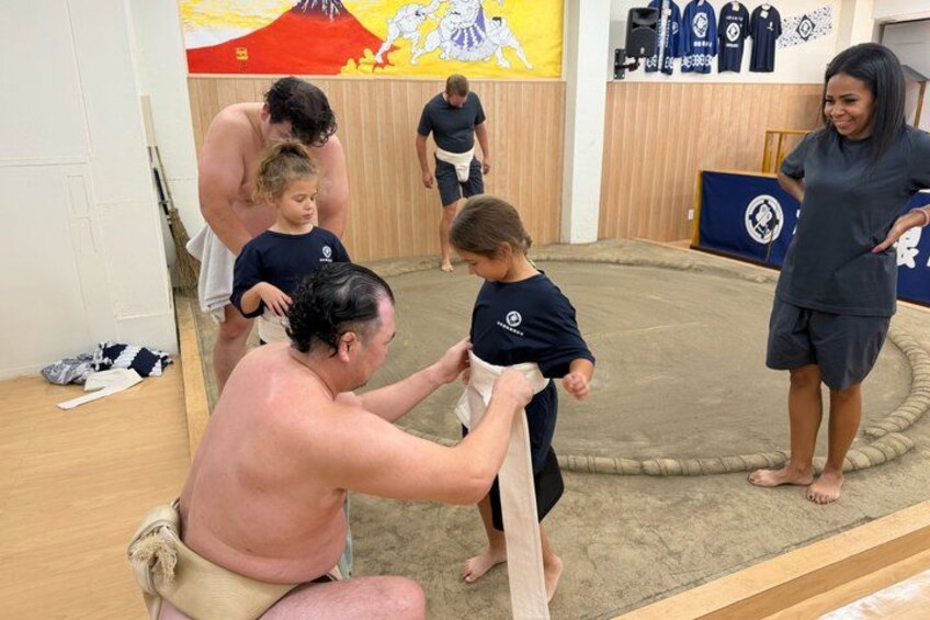 A martial arts training session with participants practicing on a padded floor. 2