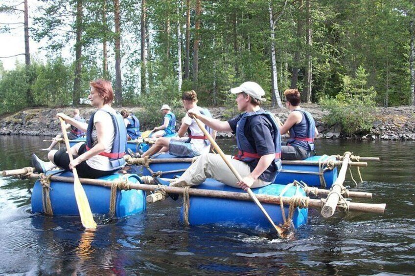 People paddling on a blue raft in a river surrounded by trees. 3