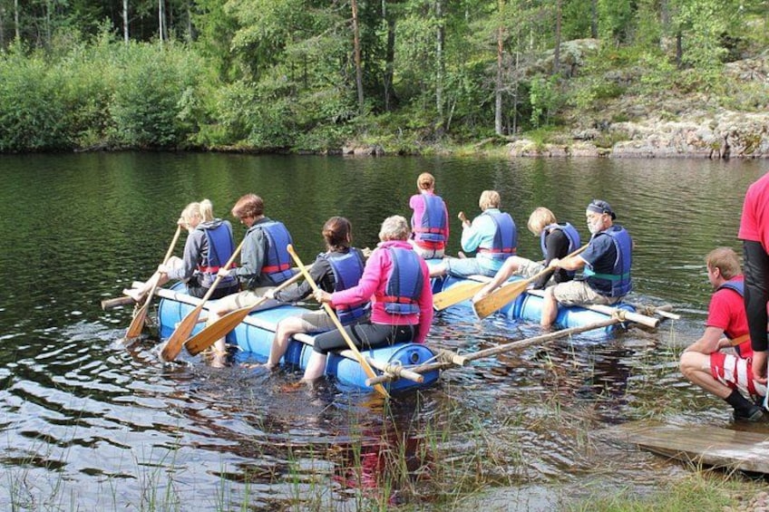 A group of people in a blue raft on a calm river surrounded by greenery. 2