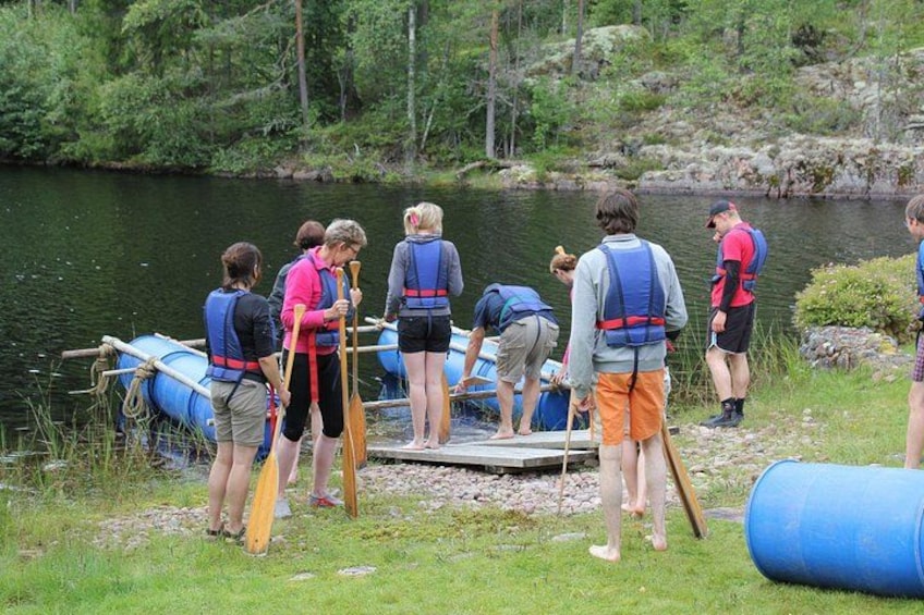People preparing for a water activity near a river with rafts and paddles. 3