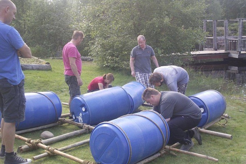 People around blue barrels in an outdoor setting with a wooden dock in the background. 4