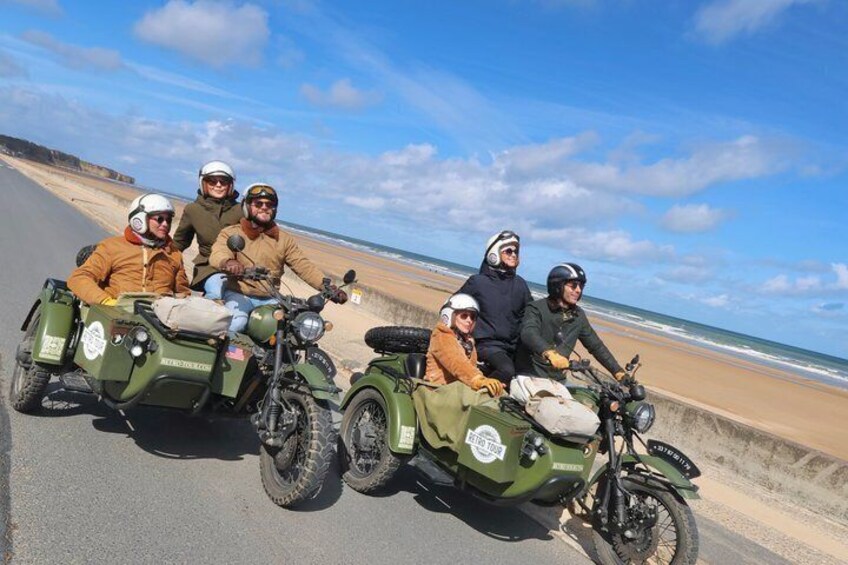 Four people on sidecars attached to motorcycles on a coastal road. 1