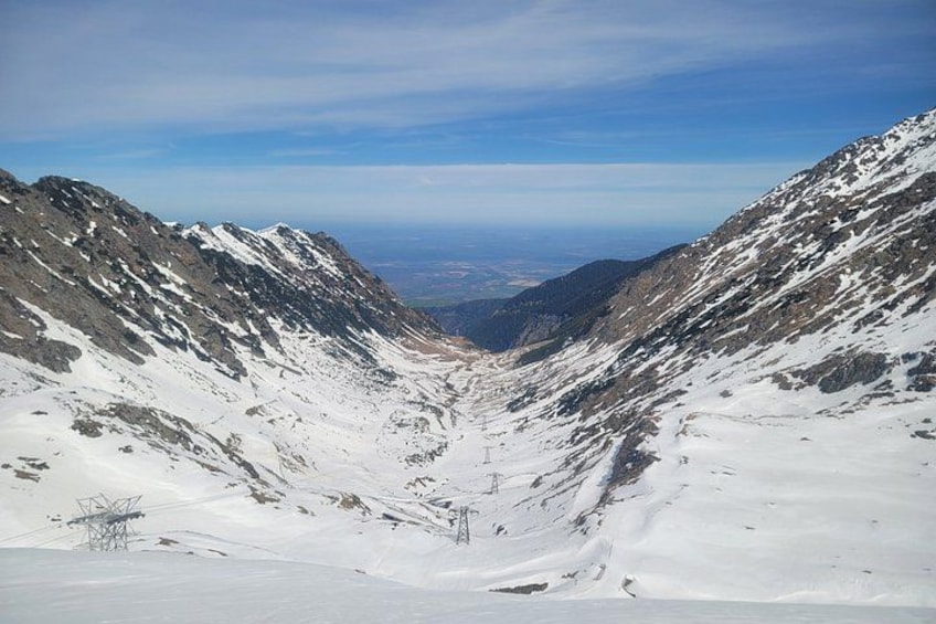 A snow-covered mountain pass with rocky terrain and distant views of the landscape. 4