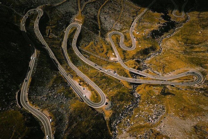 A winding mountain road with multiple lanes, surrounded by rocky terrain and sparse vegetation. 2