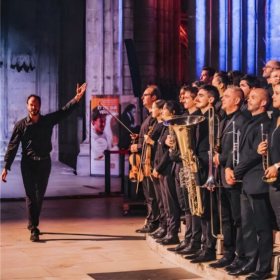En dirigent leder et orkester på scenen. 4