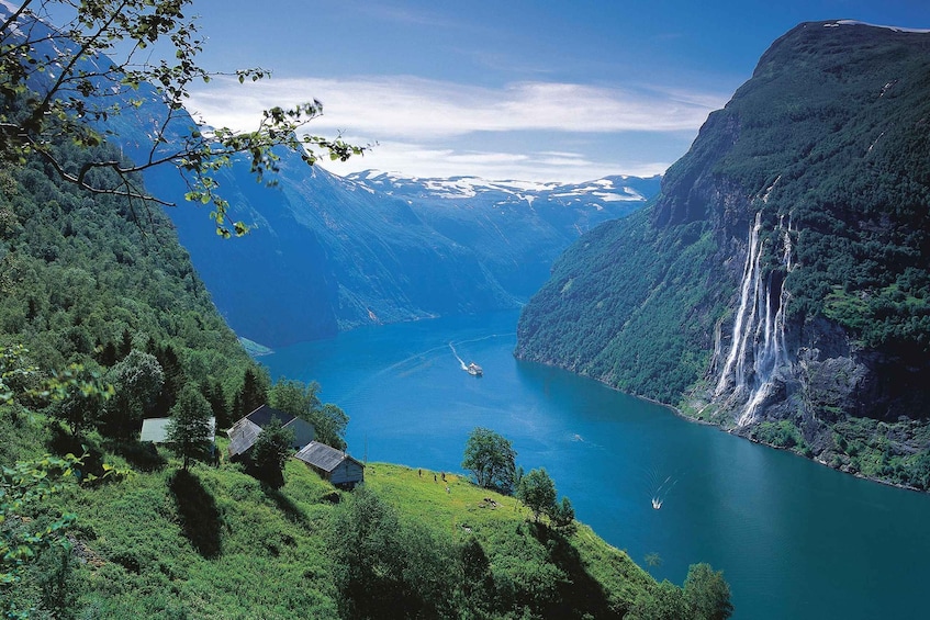 A fjord with waterfalls, a boat, and houses on a hillside. 1
